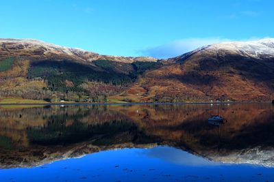 Scenic view of lake and mountains against blue sky