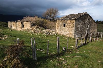 Houses in field against cloudy sky