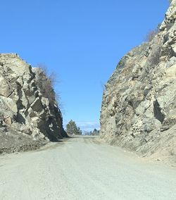 Road amidst rocks against clear blue sky