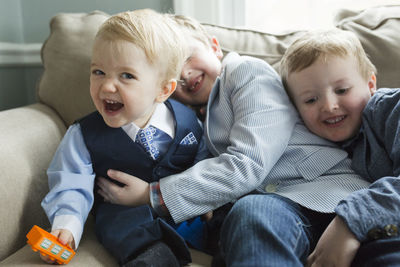 Cheerful brothers wearing suits while sitting on sofa at home during easter celebration