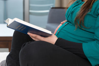 Midsection of woman reading book