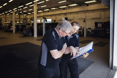 Workers discussing over documents at auto repair shop