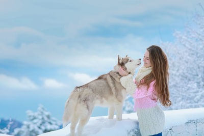 Woman with dog against sky during winter