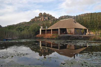 Built structure by lake and building against sky