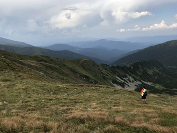 Rear view of man standing on mountain against sky