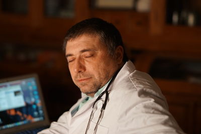 Close-up of mature doctor with eyes closed sitting in hospital