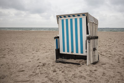 Hooded beach chair on shore against sky