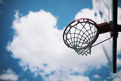 Basketball hoop with net under blue sky and white clouds