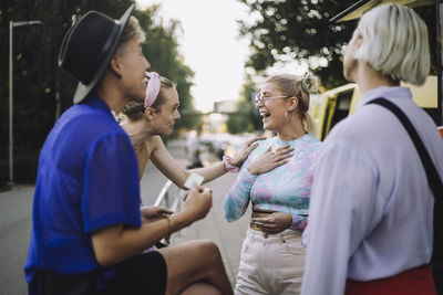 Cheerful woman wearing eyeglasses talking with non-binary friend