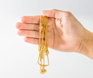 Close-up of hand holding cross against white background