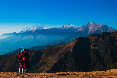 Rear view of people on mountain against blue sky