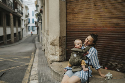 Mother with baby sitting on street