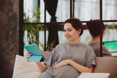 Smiling pregnant woman talking on video call at home