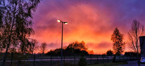 Low angle view of street lights against orange sky