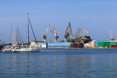 Shipyard and boats in sea against clear sky