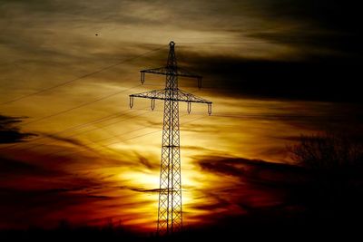 Silhouette of electricity pylon at sunset