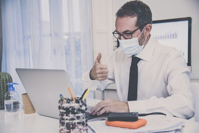 Business man with surgical masks working in the office during lockdown for coronavirus covid-19. 