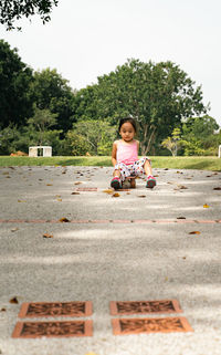 Portrait of little girl sitting on the skateboard cruising the road