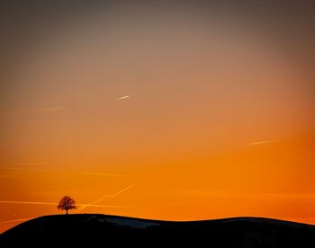 Scenic view of silhouette landscape against orange sky