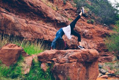 Woman doing bridge position on rocks