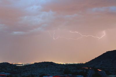 Lightning over city against sky at night