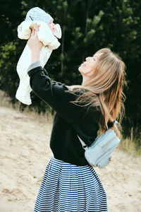 Blonde woman is happy to play with her baby girl on natural background. joyful mother and daughter.