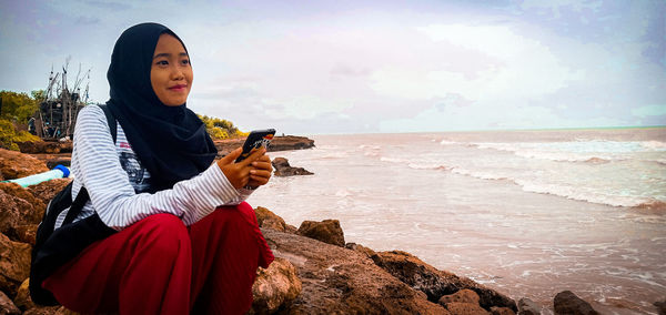 Young woman on beach against sky