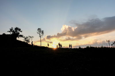 Silhouette people on field against sky during sunset