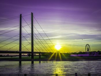 View of suspension bridge over river at sunset
