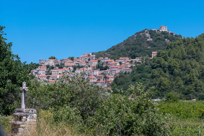 Trees and townscape against clear blue sky