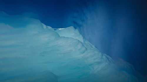 Snow covered landscape against blue sky