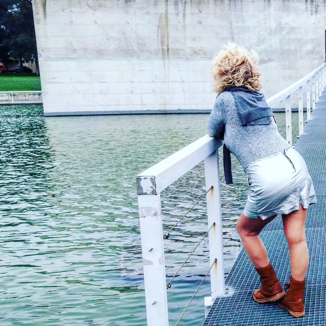 one person, water, women, full length, blue, hairstyle, adult, architecture, day, blond hair, lifestyles, rear view, casual clothing, nature, leisure activity, long hair, built structure, female, clothing, young adult, standing, railing, outdoors, footwear, dress, staircase, person, relaxation, fashion, building exterior