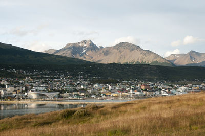 Scenic view of townscape by mountains against sky