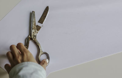 High angle view of person holding chain against white wall