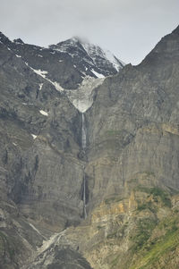 Beautiful view of snow melting and water falling down from top of rocky mountain.