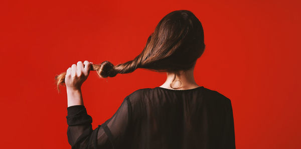 Rear view of woman standing against red background