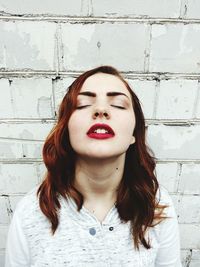 Portrait of beautiful young woman standing against wall