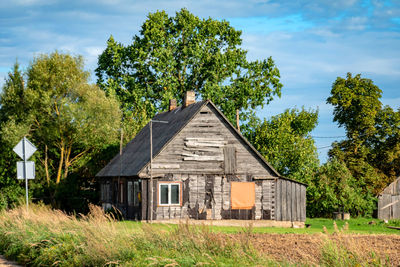 Trees and houses on field against sky