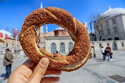 Cropped hand holding bread against hagia sophia
