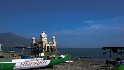 View of church at seaside against cloudy sky
