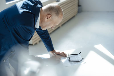 Senior businessman writing on document at desk