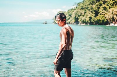 Shirtless man standing in sea at beach