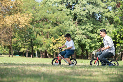 Boy riding bicycle with father on grass