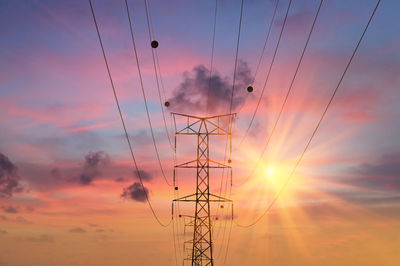 Low angle view of silhouette electricity pylon against sky during sunset