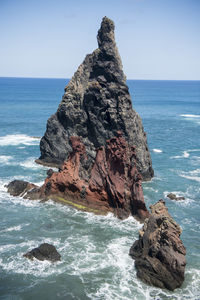 Rock formation on beach against sky