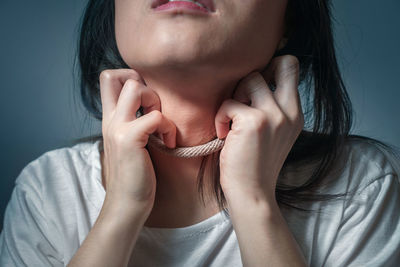 Close-up of woman holding hands against gray background