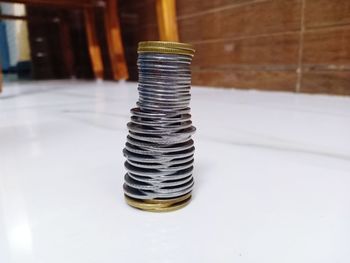 Close-up of coins stack on floor against wall