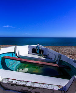 Boats moored on sea against clear blue sky