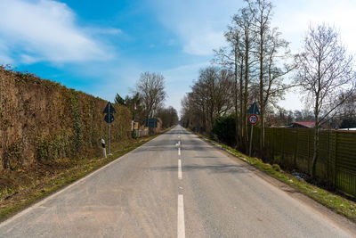 Empty road amidst trees against sky