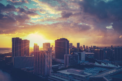 Modern buildings in city against sky during sunset
